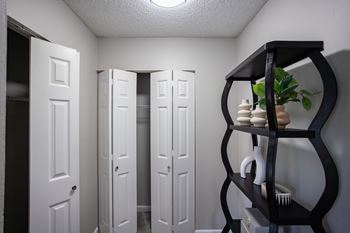 A hallway with white doors and a black shelf with a plant on it.